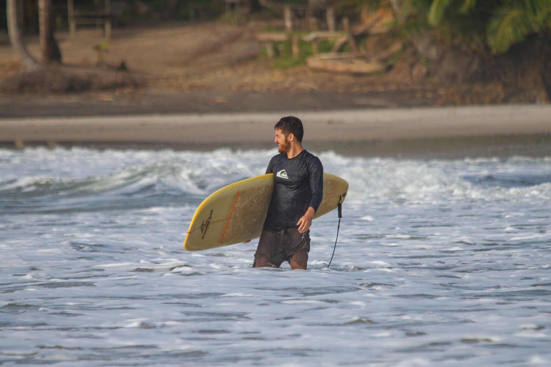 Lucas Nakata saindo do mar com a prancha de surf, ilustrando o estilo de vida do Trader Nômade